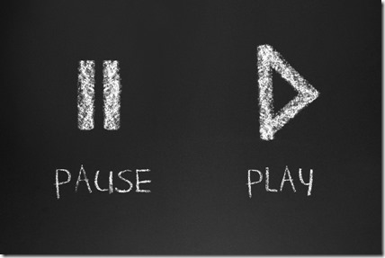 a pause and play button on black chalkboard