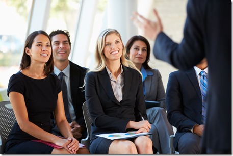 People sitting in an audience listening to a speaker