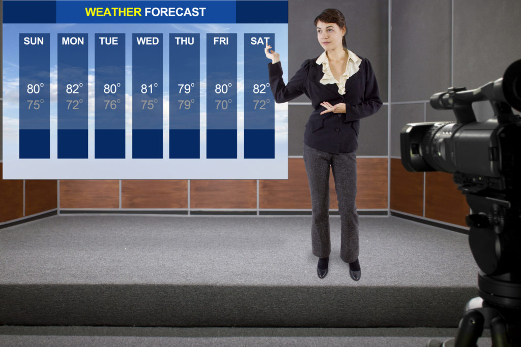 Young woman on stage with weather chart and camera