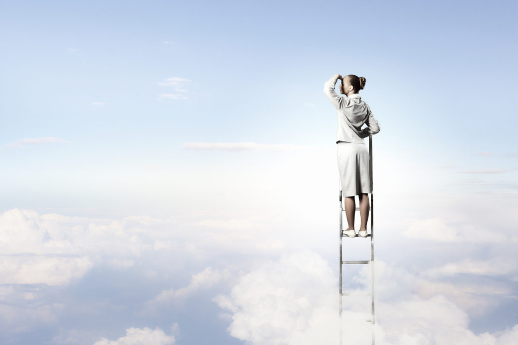 Businesswoman standing on ladder