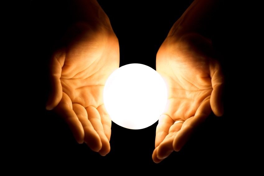 A hand holding a lighted glass orb
