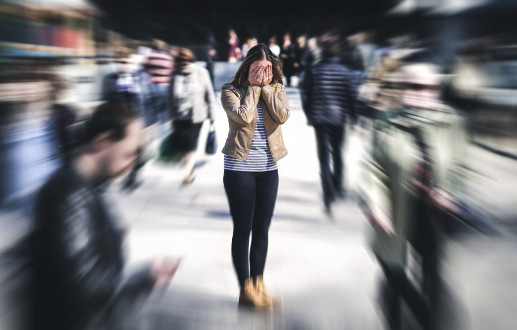 Woman having panic disorder in city, surrounded by people in the street.