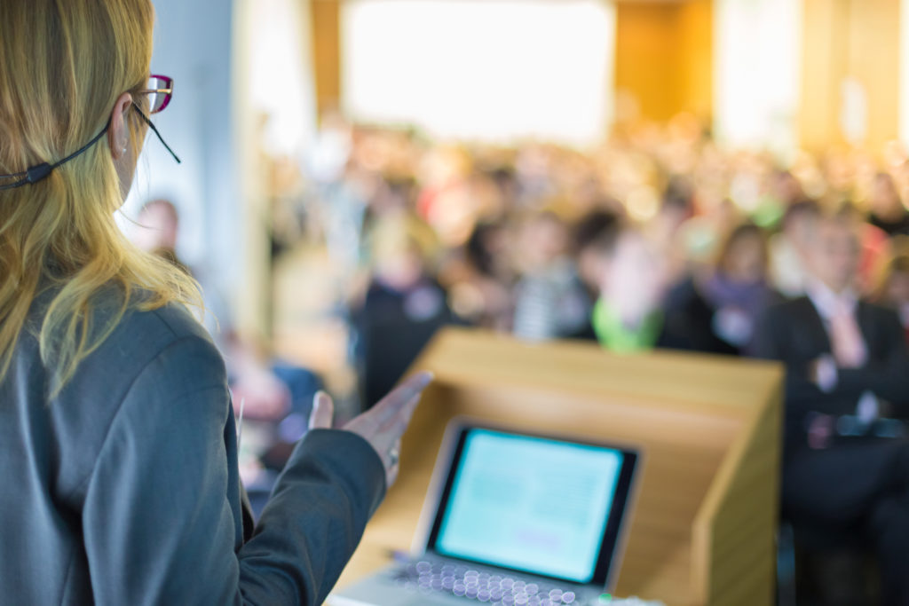 A woman delivering a speech in front of an audience