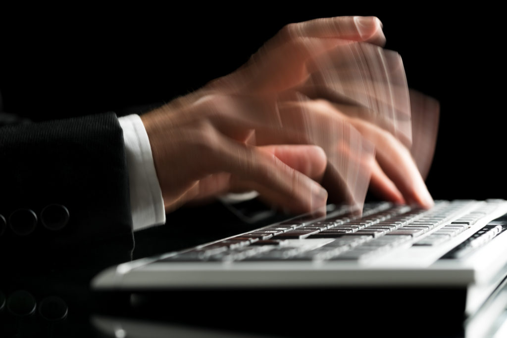 Closeup of blurred male hands typing on computer keyboard