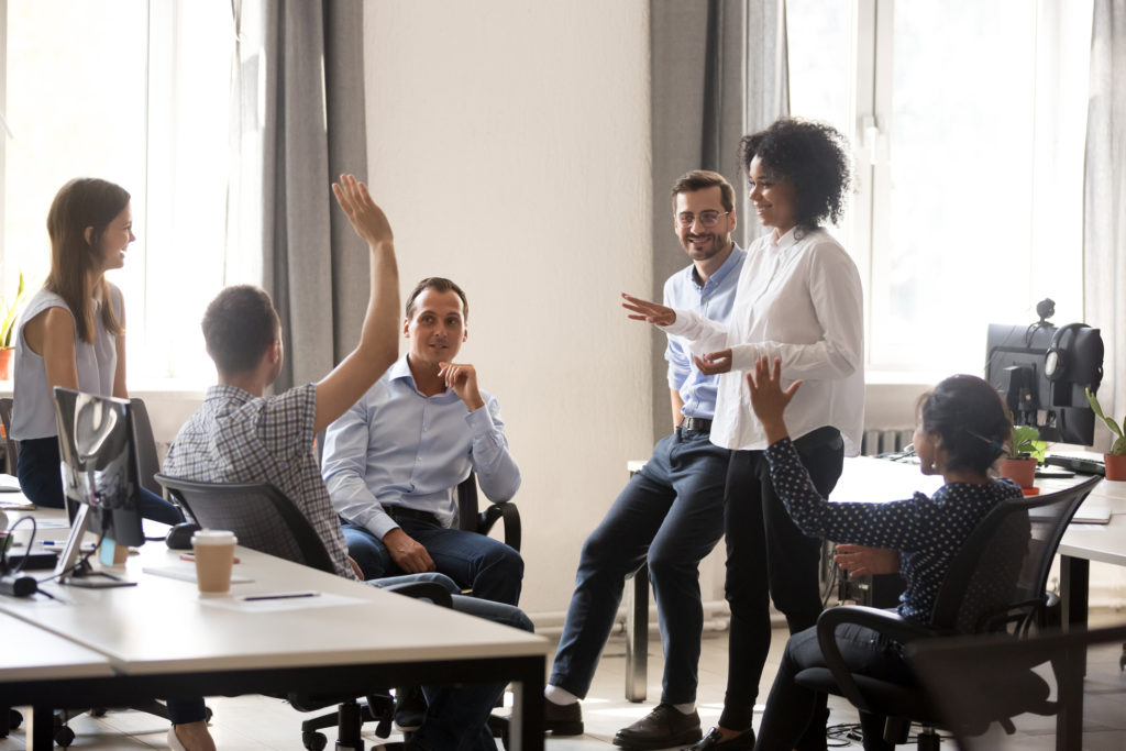 Coworkers standing around and sitting in large conference room