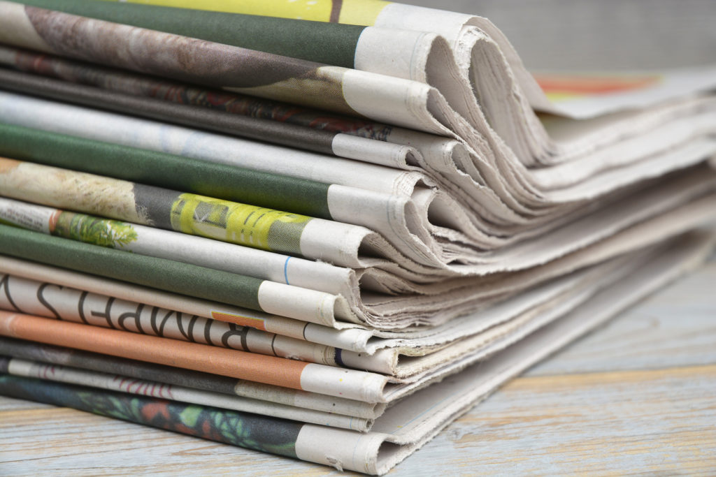 Close up of folded stacked color newspapers on grey wooden table