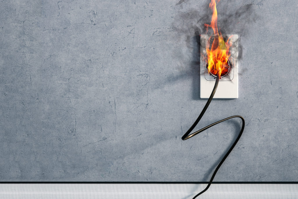 fire and smoke on electric indoor outlet on gray background