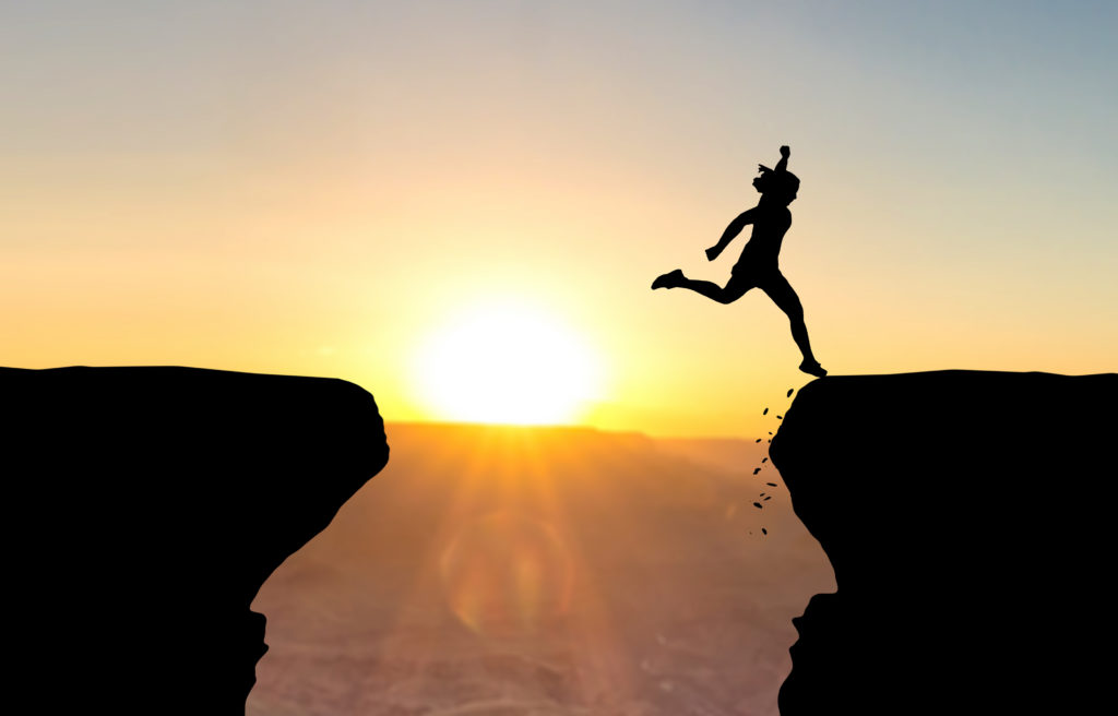 Woman landing after jumping over abyss.