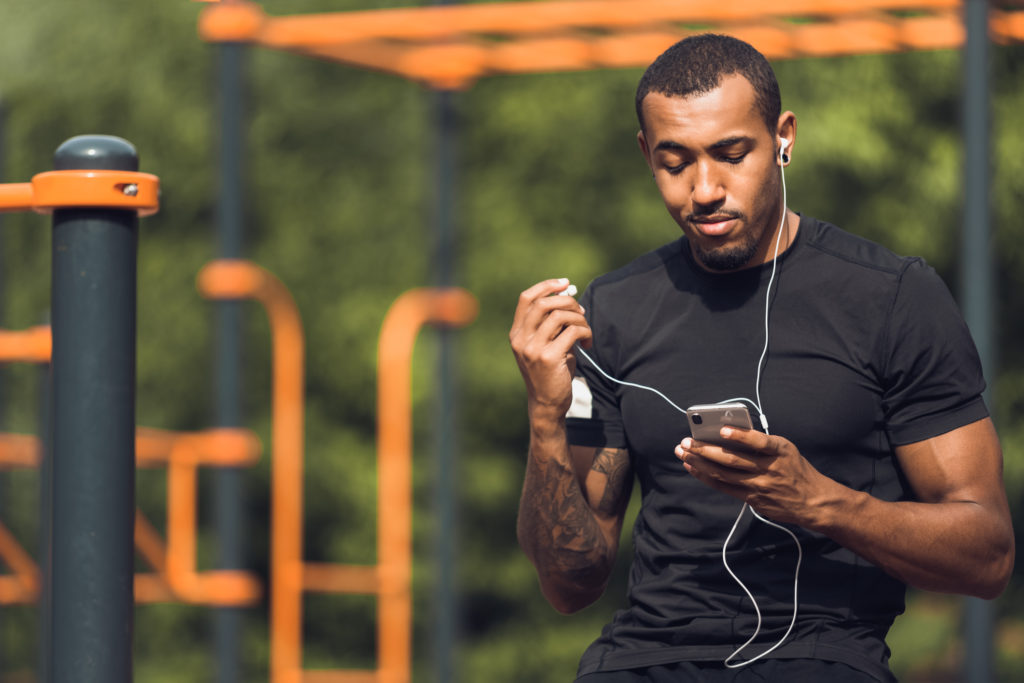 African American man listening to a podcast in a park