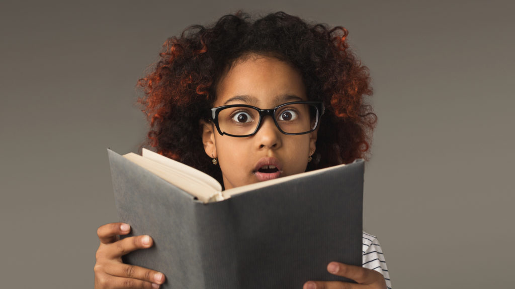 Little girl surprised by reading a book