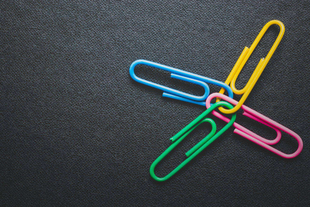 Paper clips on black background, teamwork and success concept.