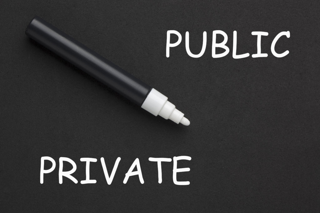 Private vs. Public written with white marker on black background.