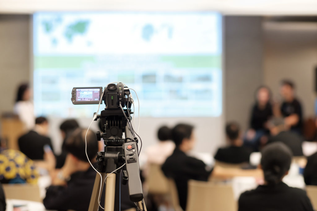 Video camera recording in seminar room.