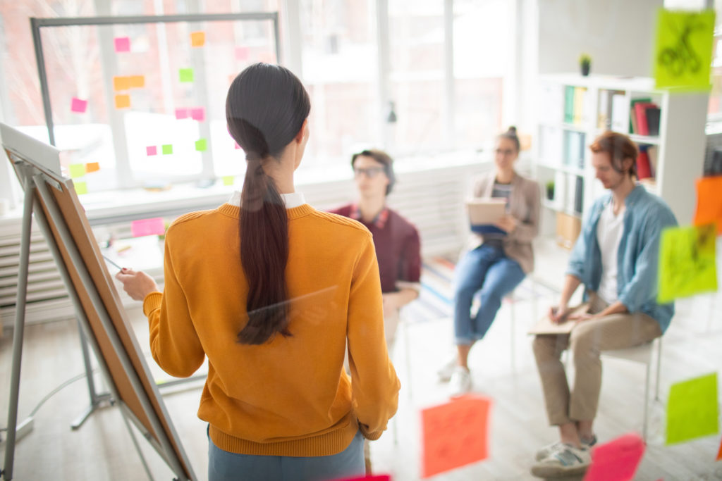 A woman at a board talking to a small audience