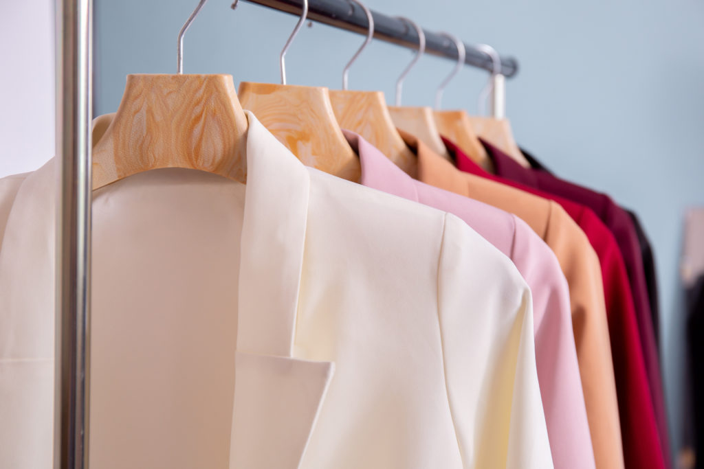 Close up of many colors of fashionable business suits hanging on rack for sale in store