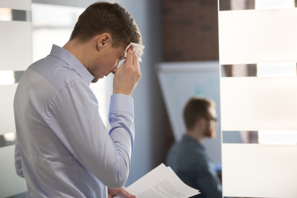 Nervous sweaty speaker preparing speech wiping wet forehead with handkerchief